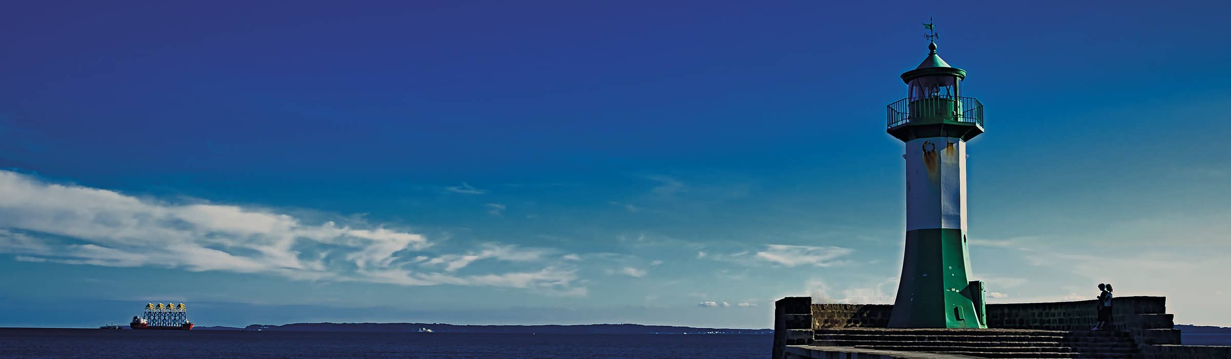 Foto eines Leuchtturms mit Meer im Hintergrund